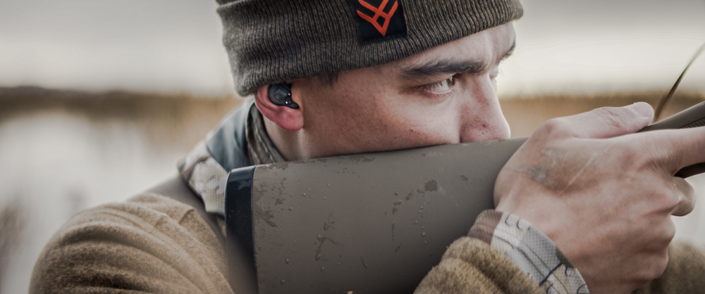 Hunter aiming a rifle in a marsh