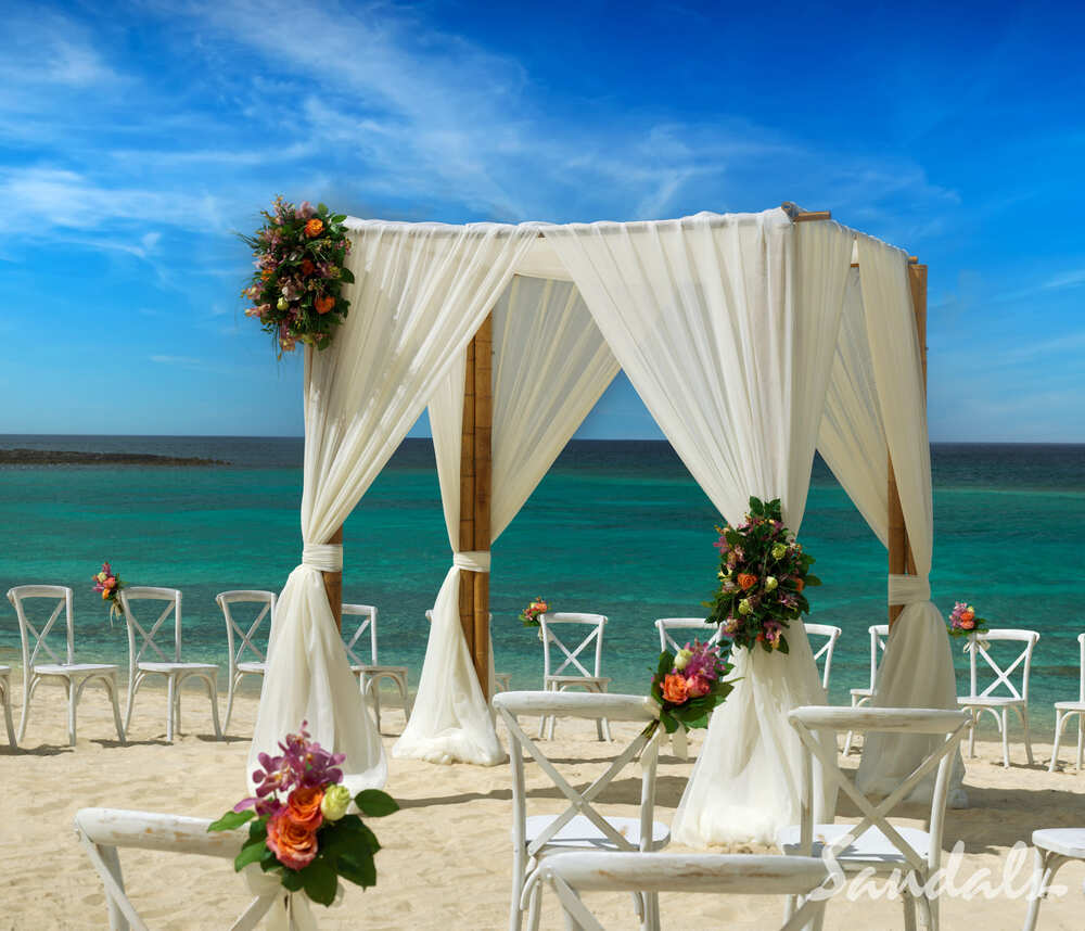 Square wedding gazebo on beach with white draping and flowers