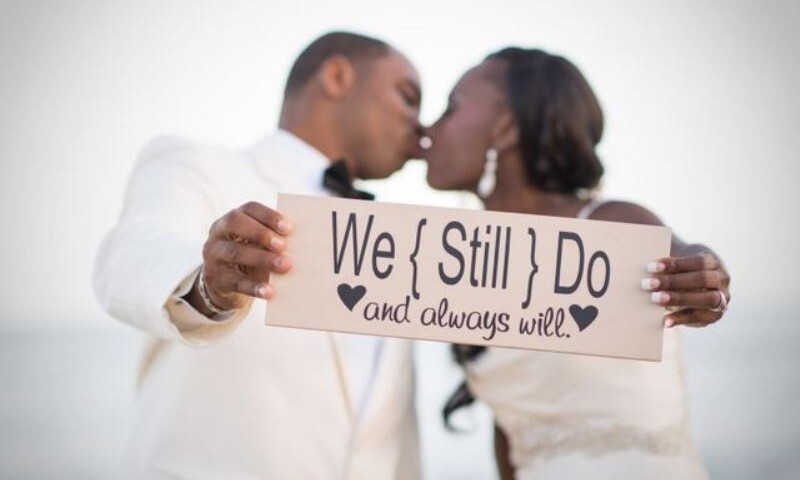 Black wedding couple holding "We Still Do" sign