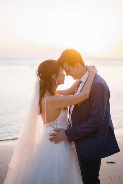 White groom and Asian bride on beach